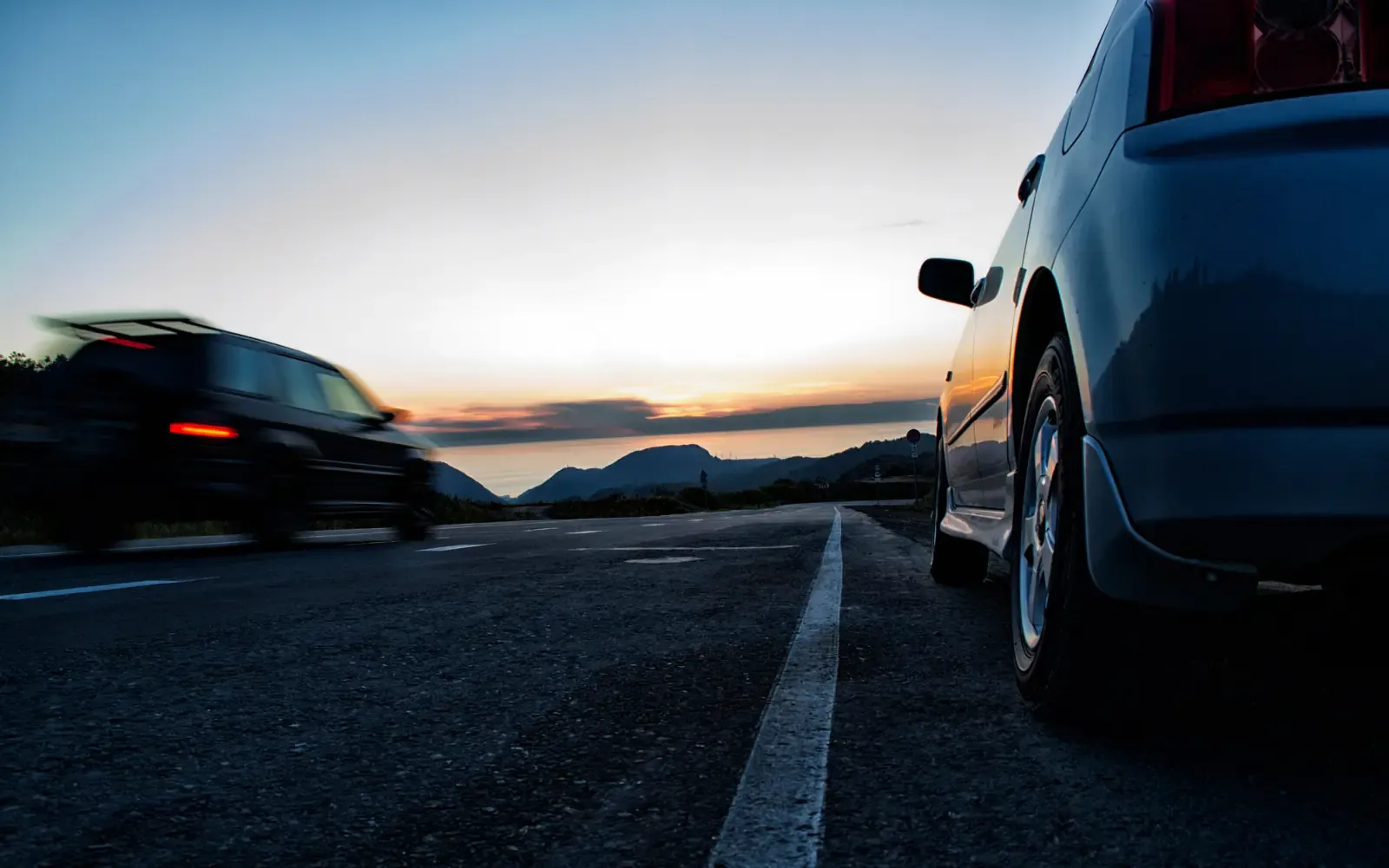 Carretera al atardecer con infraestructura eléctrica en el horizonte